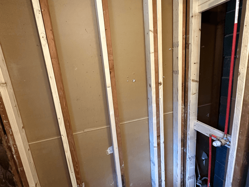 Bathroom renovation framing and rough plumbing stage in Somerville, New Jersey with exposed wall studs, PVC drain pipes, and copper water supply lines ready for new bathroom fixtures