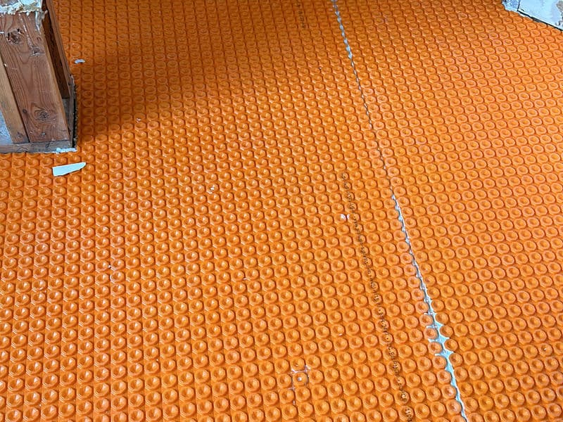 Schluter DITRA orange uncoupling membrane installed on bathroom floor during a bathroom renovation in Montgomery, New Jersey, preparing the subfloor for tile installation