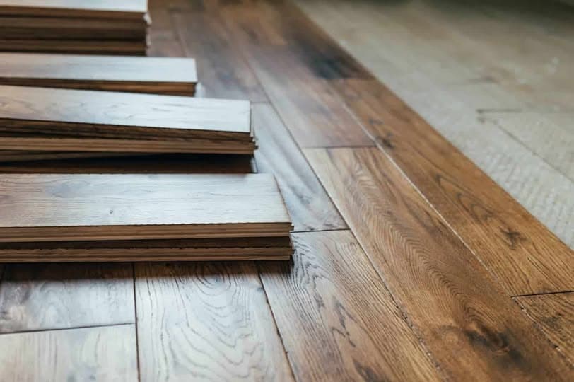 Close-up of dark walnut-stained hardwood floor planks stacked during flooring installation, showcasing rich wood grain and tongue-and-groove edges in a Bridgewater, New Jersey home
