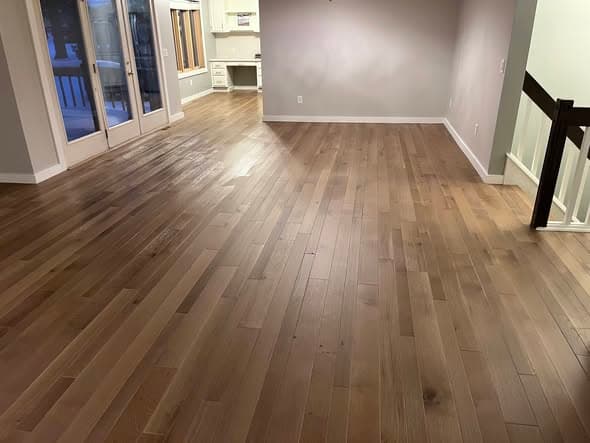 Wide-plank white oak hardwood floors in a natural warm brown tone extending through an open-concept living area with staircase railing and French doors in Bernardsville, New Jersey
