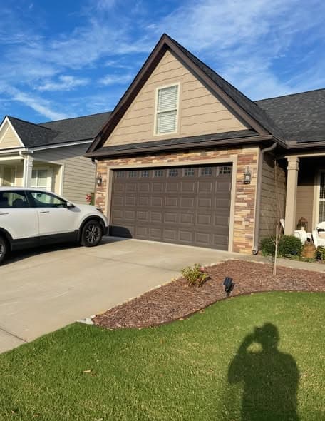 Completed exterior painting of a single-story ranch home with warm tan siding, dark brown garage door, and stone accents, professional exterior painting services in Bridgewater, New Jersey