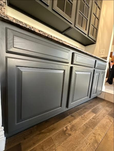Freshly painted dark charcoal gray kitchen cabinets with raised panel doors beneath a granite countertop, professional cabinet painting services in Bernardsville, New Jersey