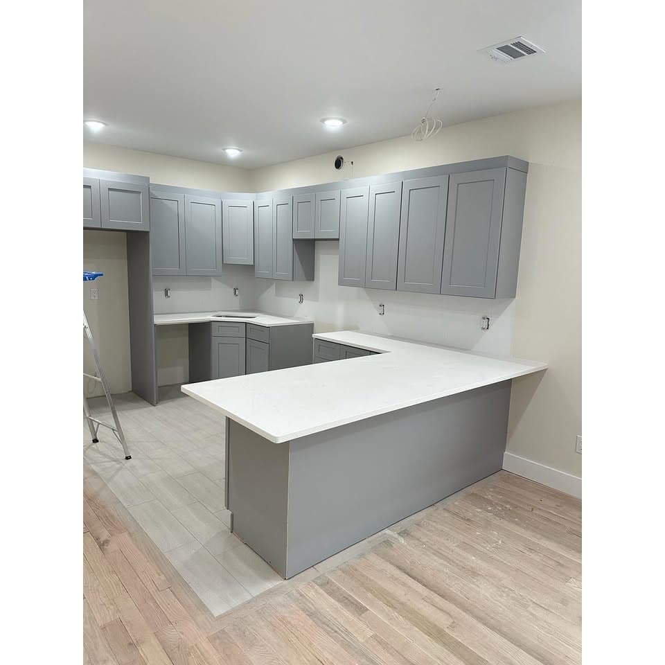 Modern kitchen renovation featuring wood-look porcelain floor tile installation with gray shaker cabinets and white quartz countertop island, completed in Bridgewater, New Jersey