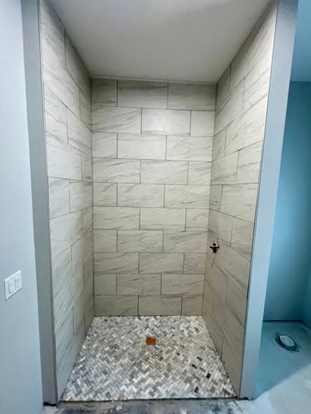 Completed walk-in shower featuring gray marble-look large-format wall tile installation and small herringbone mosaic marble tile shower floor with center drain, bathroom renovation in Hillsborough, New Jersey